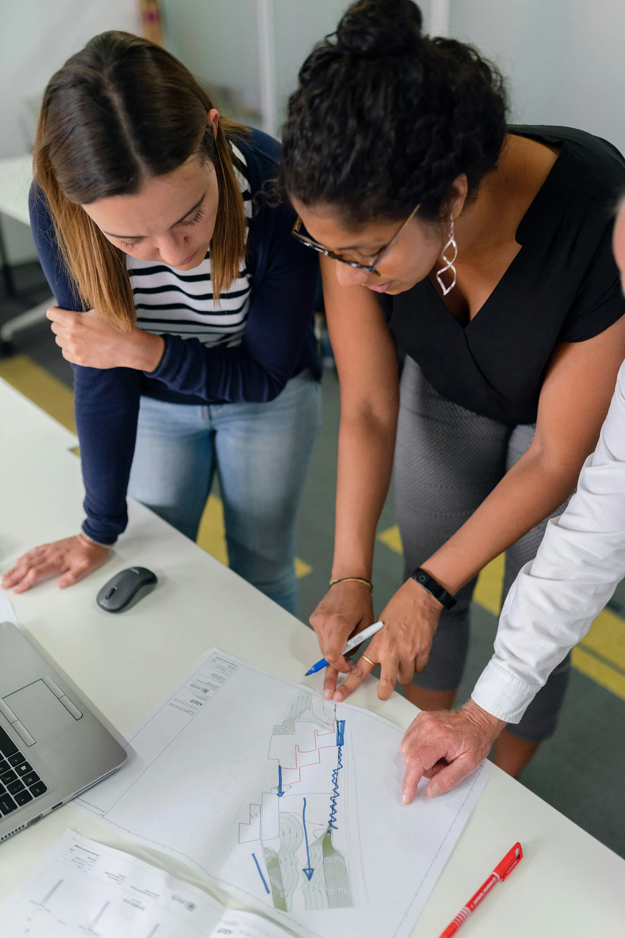Zwei Frauen und ein Mann zeichnen Change Roadmap auf Blatt im Change Agent Training