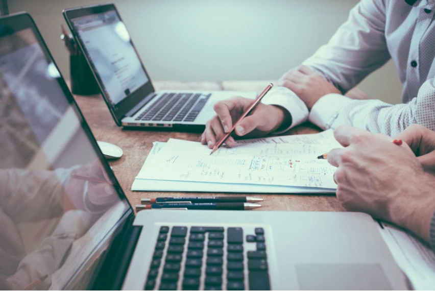 Mitarbeiter analysieren Daten mit Laptops und Papier